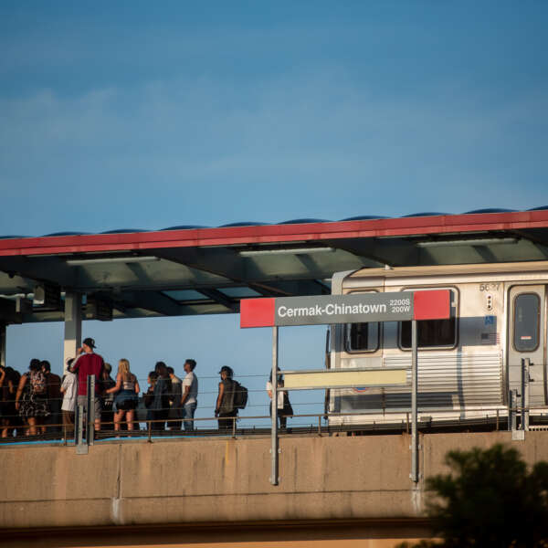 A crowd of people waits on the Cermak-Chinatown Red Line CTA platform as a train approaches.