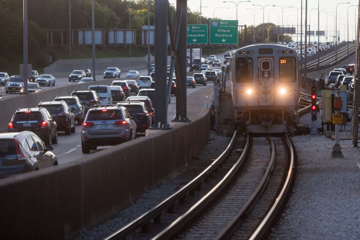 An L train riding on its tracks on the highway.