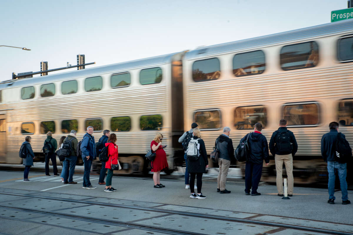 Numerous people standing, waiting for Metra train to stop.