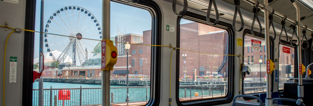 View of Navy Pier ferris wheel and lake from inside a bus window.