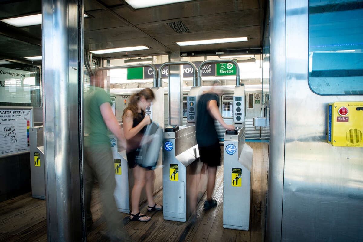 People passing through turnstile at CTA Green Line stop.