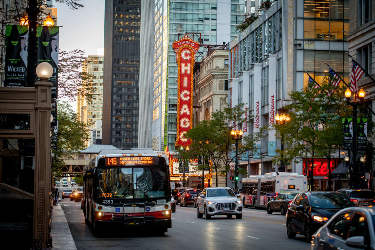 Downtown Chicago street with 2 CTA buses and cars driving past.