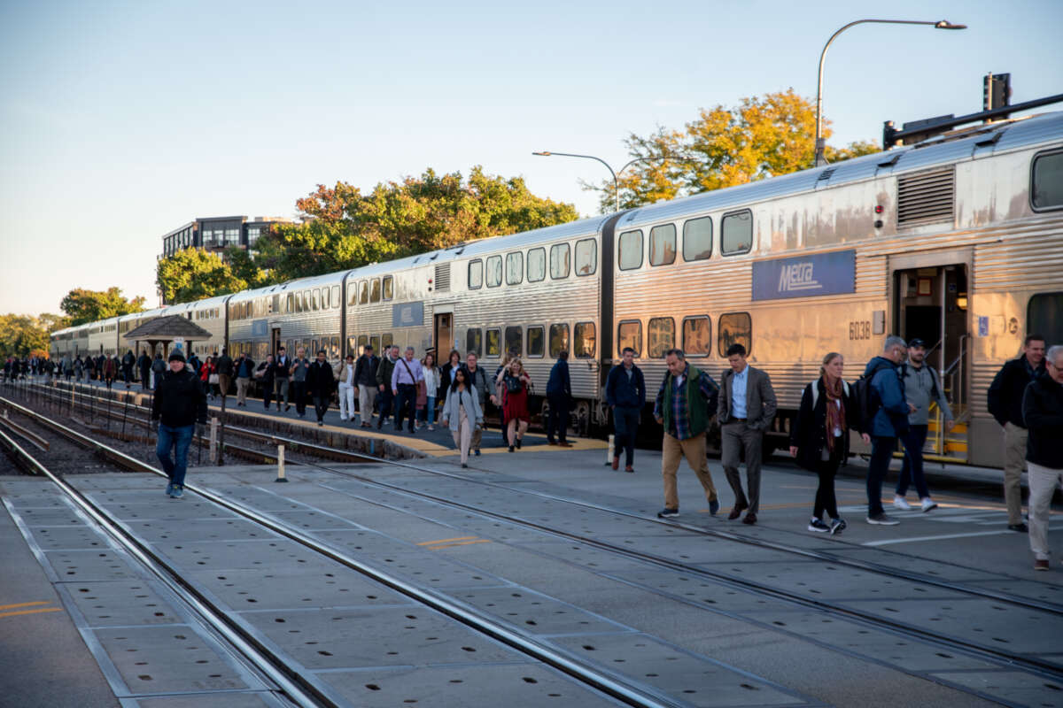 Large group of commuters exiting a stopped Metra train.