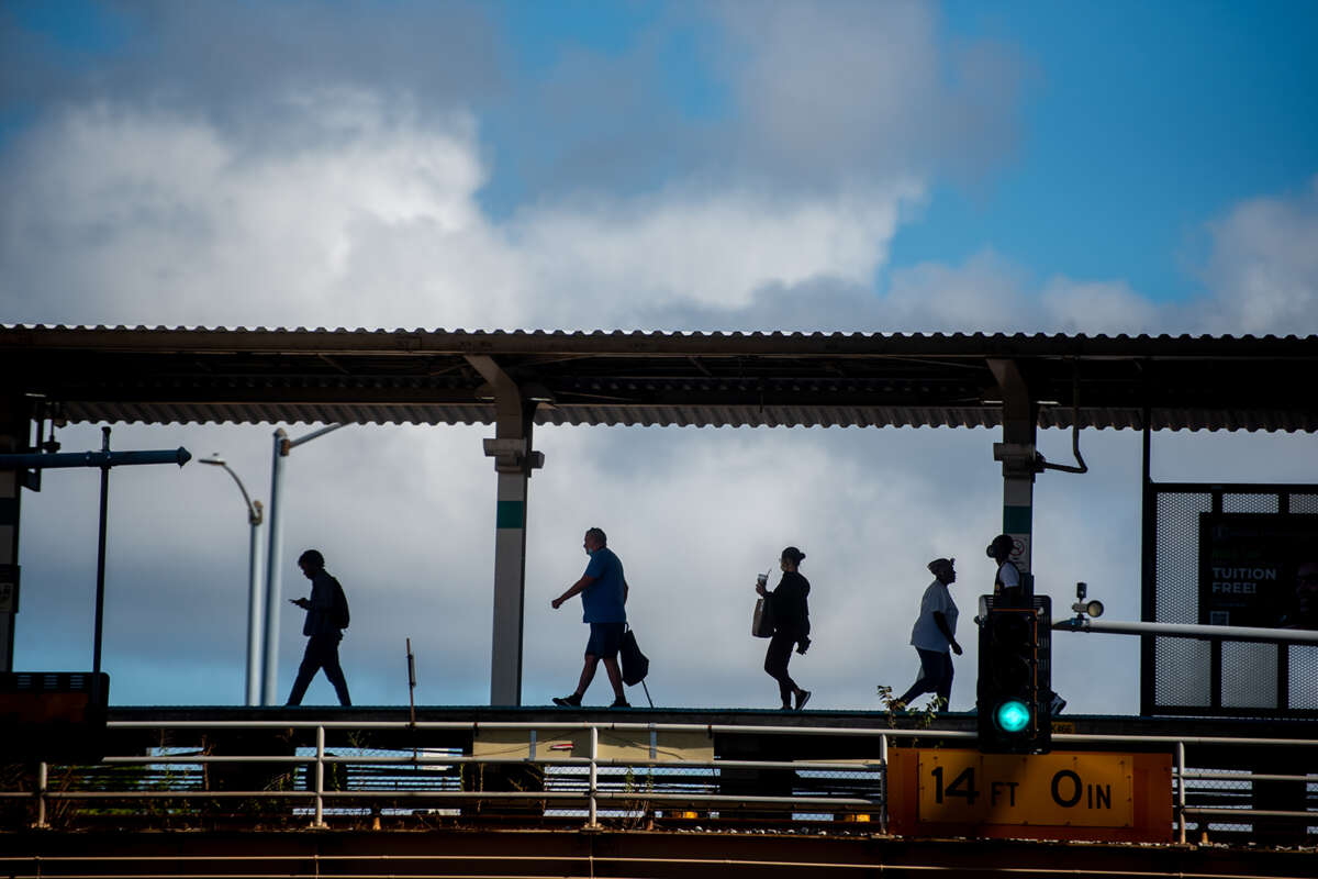 Silhouette of people walking at Oak Park train stop.