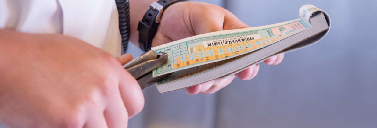 Metra train service employee punching tickets.